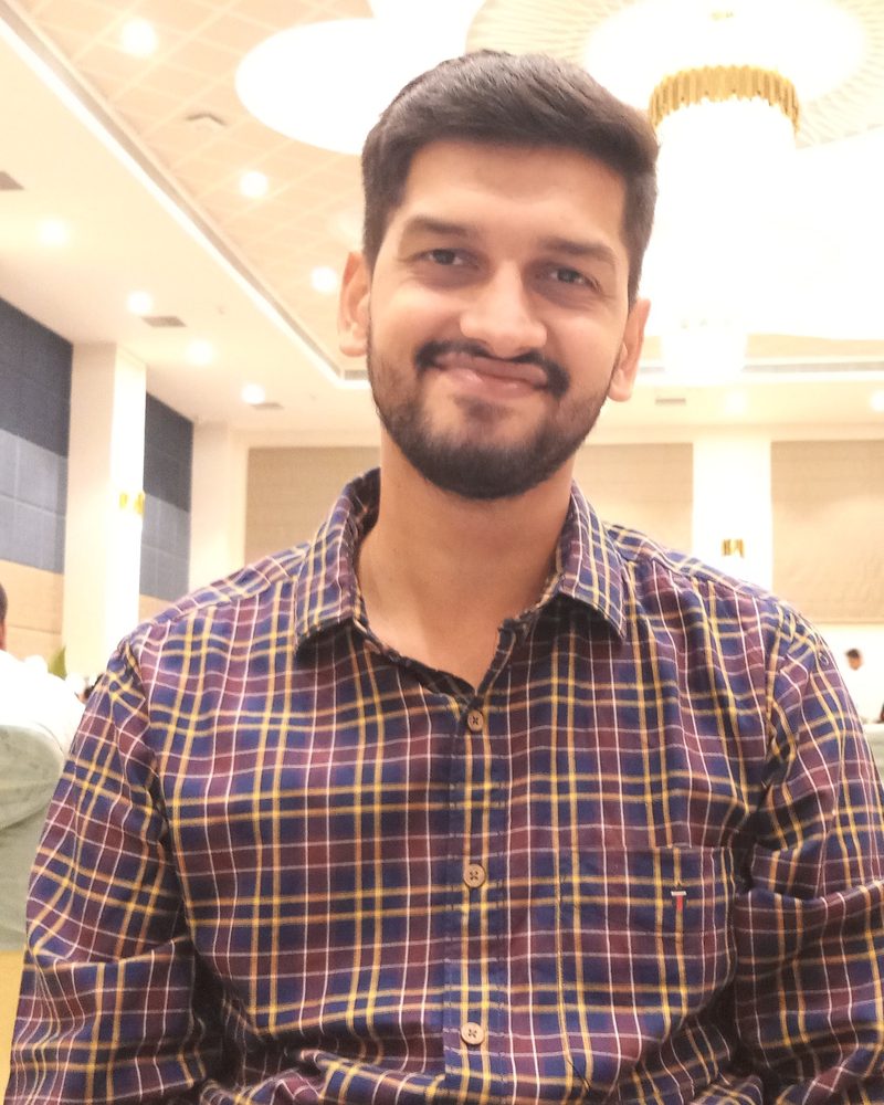 Tanveer Singh, smiling, in a checked shirt